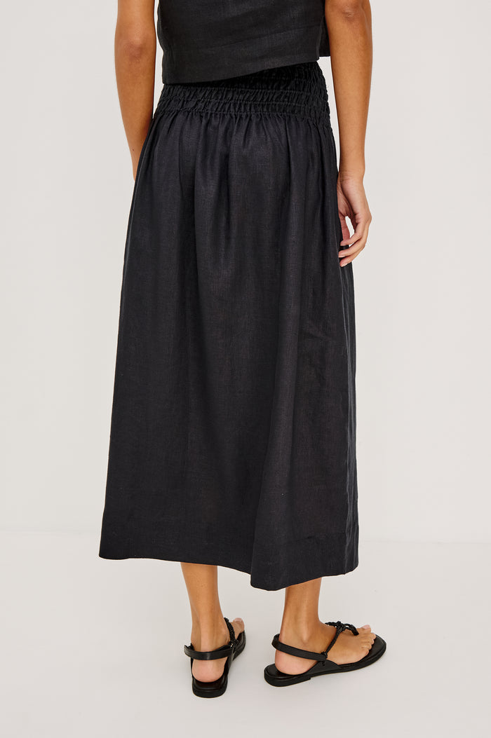 Alessa Midi Skirt in Heavy Linen With Wide Smocked Waistband and A-Line Silhouette in Black Linen Colorway - Lower Body Back View Featured on Model