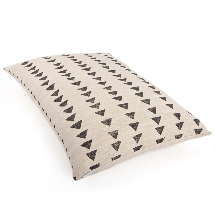 Close-up side view of THE FOGGY DOG's DOG BED (M, AMANI SAND) in beige fabric with black hand-painted triangles. Its boho style and textured weave are highlighted as it rests on a white surface, showing off its soft structure.
