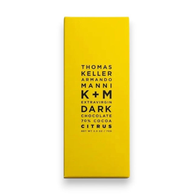 A bright yellow wrapper with centered black text: "K & M EXTRAVIRGIN CHOCOLATE K+M - EXTRAVIRGIN DARK CHOCOLATE CITRUS BAR, Net Wt 2.5 oz / 70g.