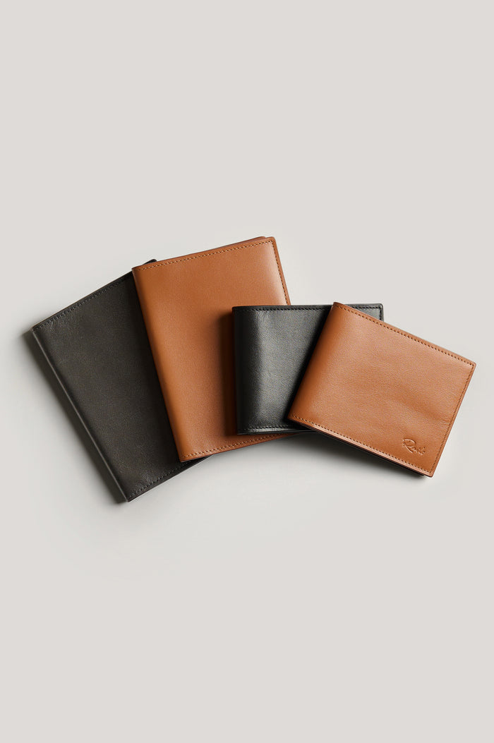 Leather wallet in black color, folded. Front view next to passport holders featured.