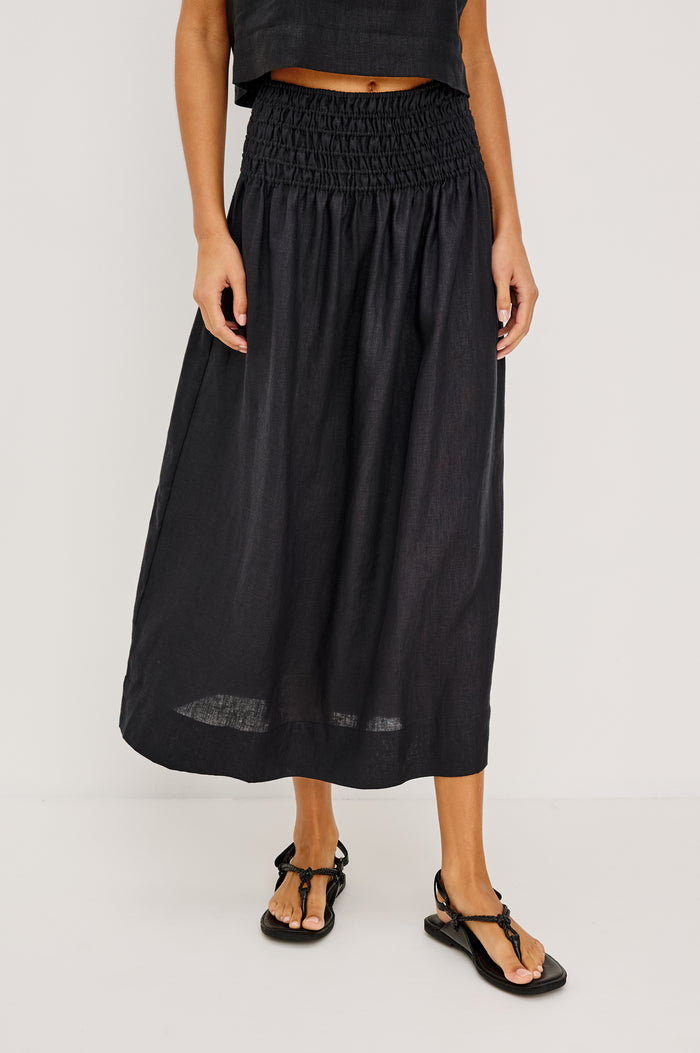 Alessa Midi Skirt in Heavy Linen With Wide Smocked Waistband and A-Line Silhouette in Black Linen Colorway - Lower Body Front View Featured on Model