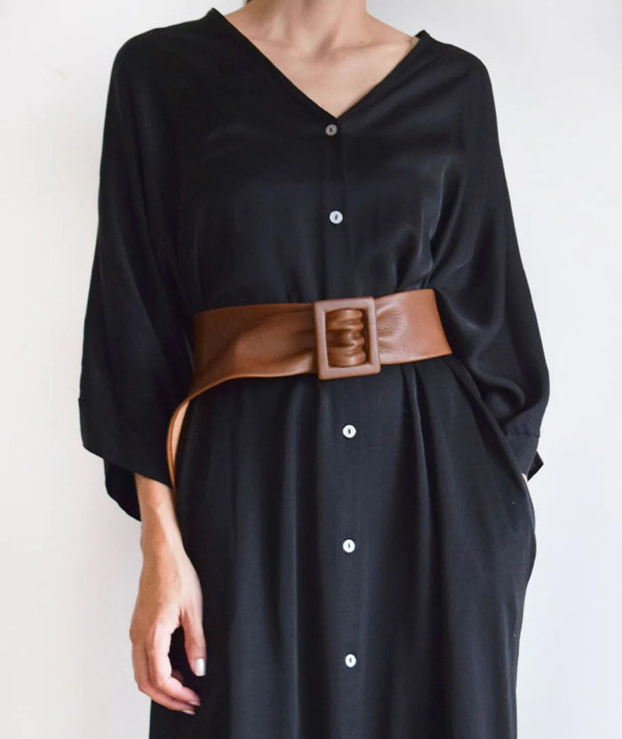 The APROPOS BELT by ADA is a handcrafted brown leather belt with a wide band and smooth texture. Made from genuine Argentinian leather, it features a rectangular buckle, showcased on a plain white background.
