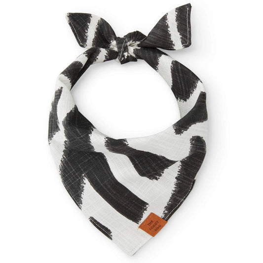 THE FOGGY DOG's BANDANA (L, EBONY ZEBRA): A handmade white slub cotton bandana featuring bold black brushstroke patterns and a small brown leather patch, tied in a loose knot. Made in San Francisco.