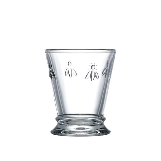 The BEE TUMBLER by LA ROCHERE is a clear glass with a slightly flared rim, featuring an embossed Napoleonic bee pattern—an elegant addition to your everyday glassware collection.