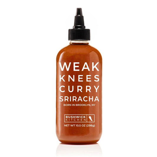 A 10.5 oz (298g) bottle of BUSHWICK KITCHEN 'WEAK KNEES' CURRY SRIRACHA SAUCE with a black twist cap, white front text, and a Gochujang chile paste blend for a unique flavor kick.