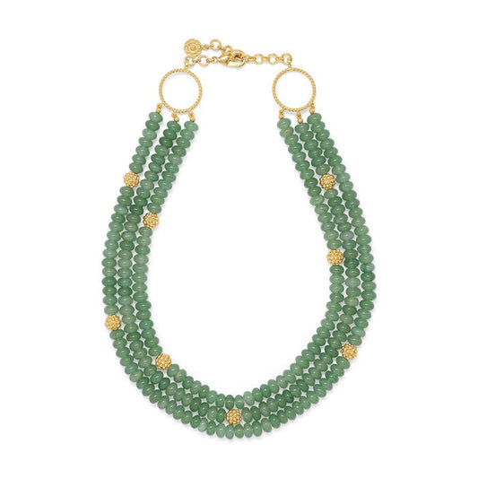 The CAPUCINE DE WULF - BERRY AND BEAD TRIPLE STRAND NECKLACE MEADOW JADE is a striking accessory with triple strands of jewel-toned jade beads, accented by small gold spheres and two large gold rings near the adjustable clasp.