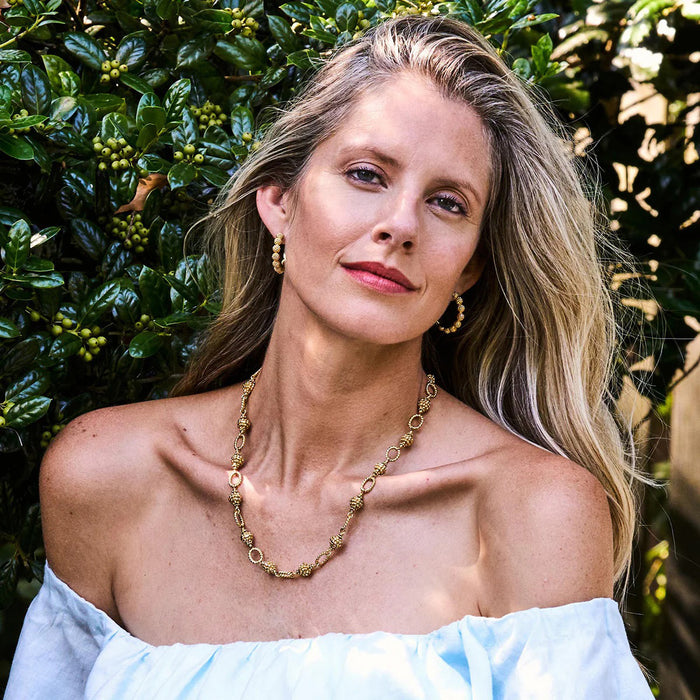 Explore the exquisite charm of CAPUCINE DE WULF's BERRY ICON SMALL HOOP EARRINGS. Their textured, beaded design resembles golden berries, and the front and side views showcase their intricate detailing.