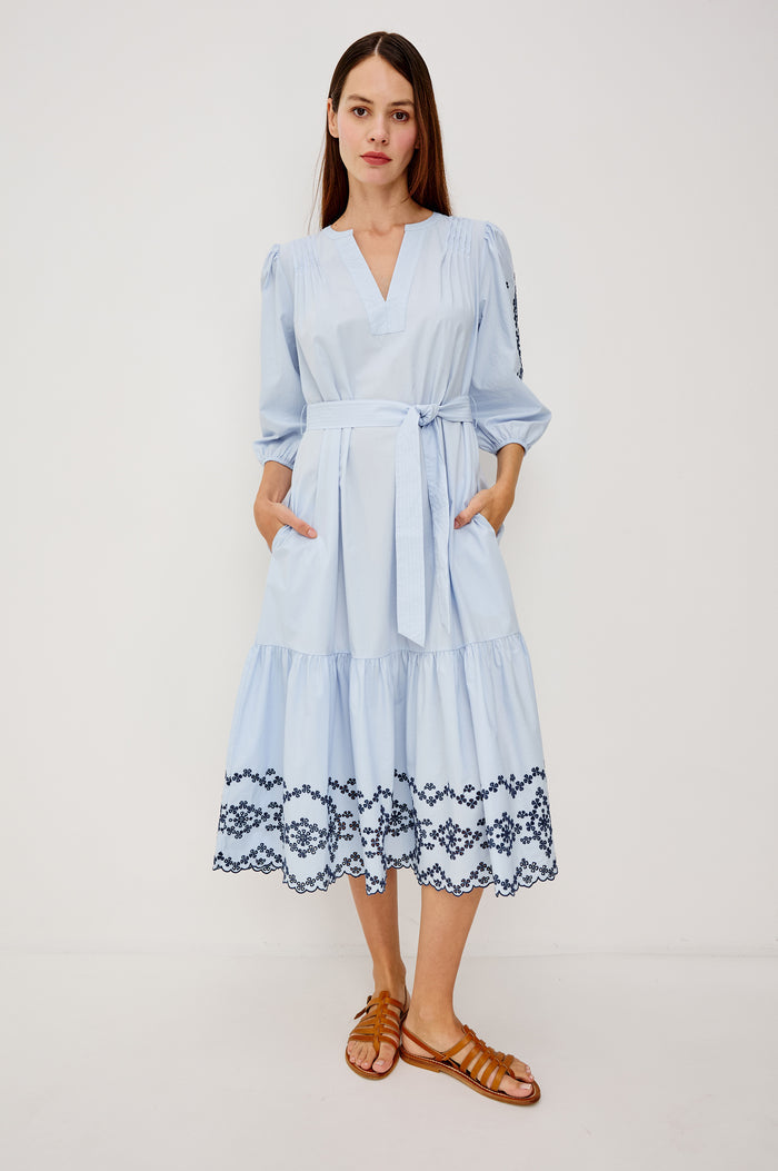 Carmel Peasant Maxi Dress in Poplin With Pleated Shoulders, V-Neckline, Three-Quarter Puff Sleeves, Adjustable Waist Ties, Side Pockets, Tiered Seam, and Contrast Embroidery at Cuffs and Hem in Blue Bird Colorway - Full Body Front View Featured on Model