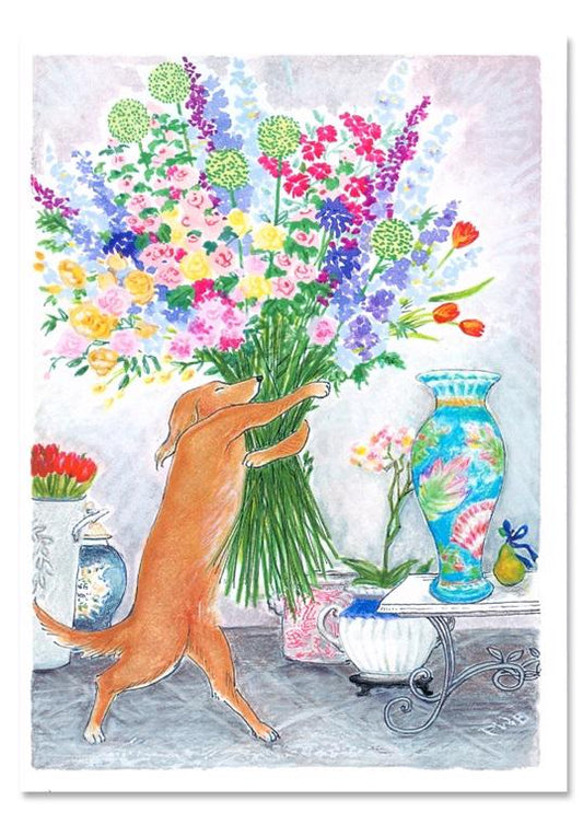 A brown dog stands on its hind legs to sniff a large, colorful CIAO BELLA - BIG BOUQUET CARD by CIAO BELLA displayed in a vase on a table, next to decorative vases, a pear, and an envelope with blank note card.