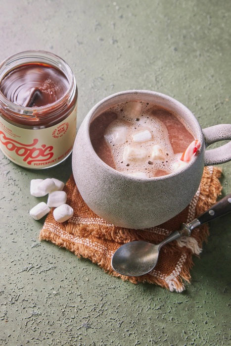 A jar of COOPS PEPPERMINT HOT FUDGE features rich European chocolate and refreshing peppermint oil. Its cream-colored label with red lettering highlights this decadent chocolate sauce from the brand COOPS.