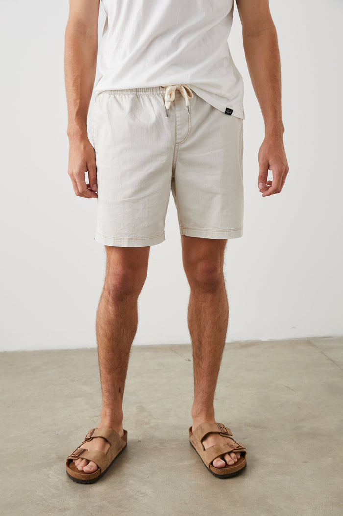 Cruz Shorts with a Drawstring Waist, Two Front Pockets, Two Back Button Flap Pockets in Natural Colorway - Front View Featured on Model