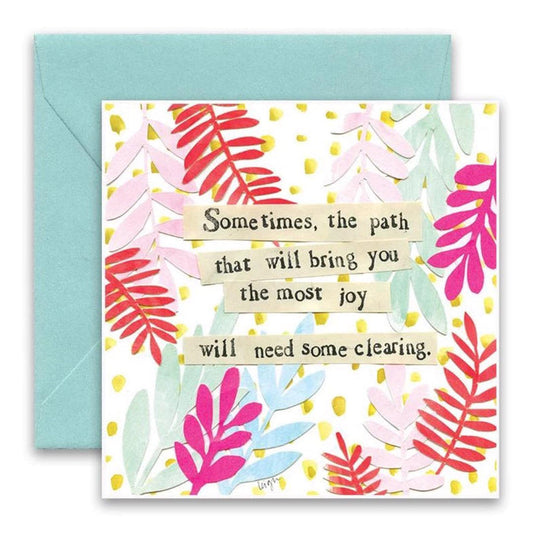 The CURLY GIRL DESIGNS - NEEDS CLEARING GREETING CARD from CURLY GIRL DESIGN, INC features pastel pink, red, and green leaf collage art with gold dots and the message: "Sometimes, the path that will bring you the most joy will need some clearing." Includes blue envelope.
