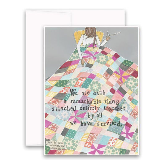 The CURLY GIRL DESIGNS - STITCHED TOGETHER CARD by CURLY GIRL DESIGN, INC features art of a person sewing a vibrant quilt with the message: "We are each a remarkable thing stitched entirely together by all we have survived." Card and envelope included.