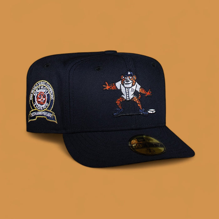 A navy blue Detroit Tigers baseball cap with a cartoon tiger mascot on the front andanniversary badges on the sides.