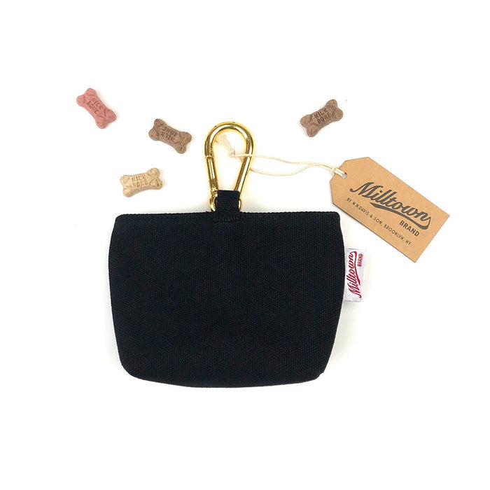 A small black DOG TREAT CASE (ONYX) from MILLTOWN BRAND with a gold magnetic closure is displayed on a white background, surrounded by five bone-shaped dog treats.