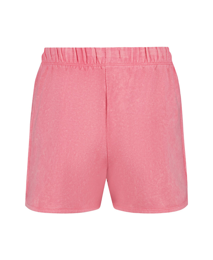 Back view of Girls' Sunset Short surf shorts by Roxy in pink, featuring an elastic waistband and soft baby French terry fabric, shown on a plain white background.