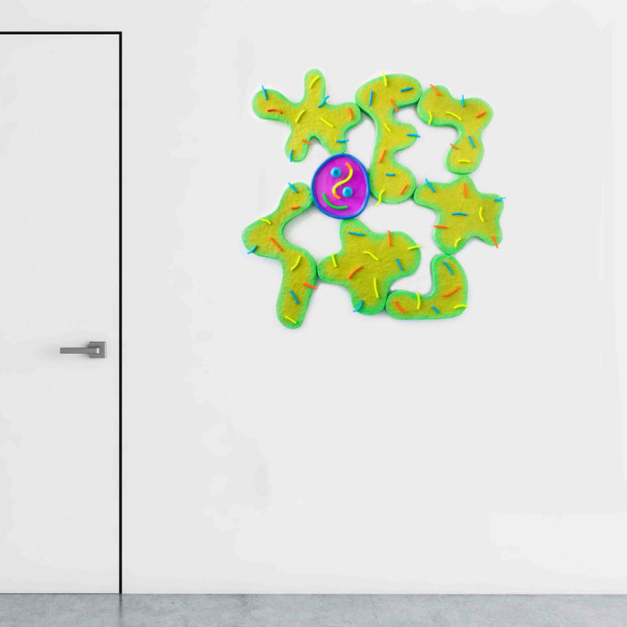 The artwork 'Good Germs' by Ryan Patrick Martin features abstract, organic shapes in vibrant yellow-green tones arranged in a playful puzzle-like pattern, centered around a deep purple circular resin pool with curved smile-like lines. The mixed-media piece combines wood, epoxy, and acrylic paint in a whimsical 40x40 inch composition.