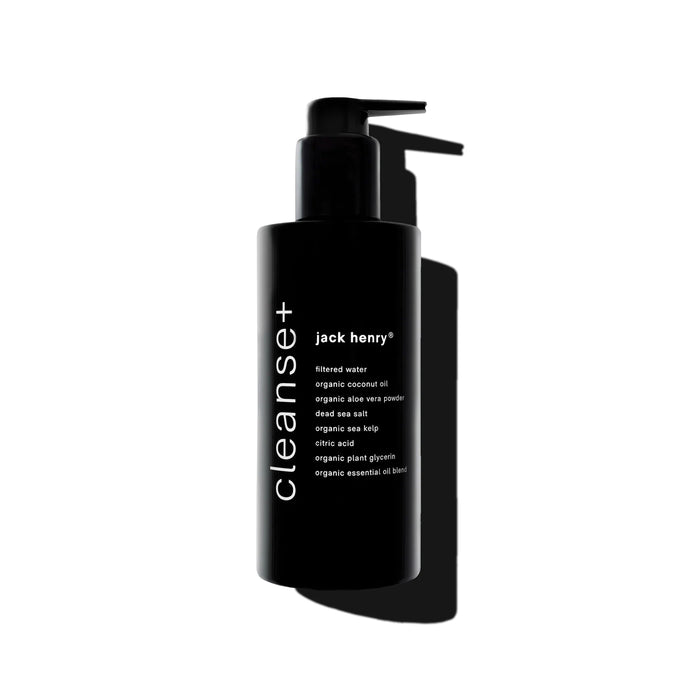 A sleek black pump bottle labeled "JACK HENRY - CLEANSE+ FACE" features hydrating botanicals and natural ingredients. Photographed on a white background with a bold shadow, this all-in-one cleanser combines purity and simplicity.