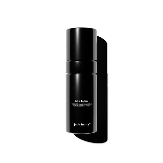 A sleek black bottle of JACK HENRY - HAIR FOAM, featuring minimal white text on the front, casts a shadow on a white background.