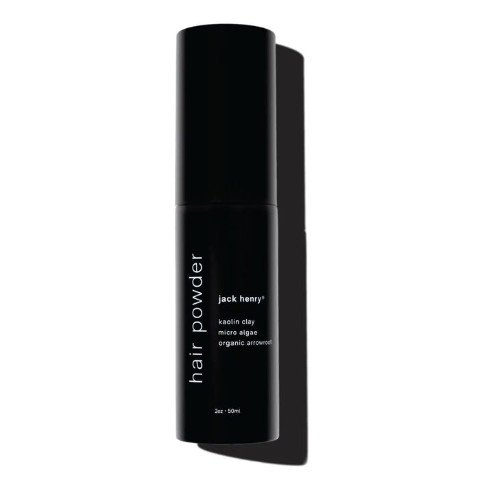 A shirtless person holds a black JACK HENRY – HAIR POWDER bottle, a dry shampoo with smectite, micro algae for growth and shine, and arrowroot to absorb oil—leaving hair clean and matte.