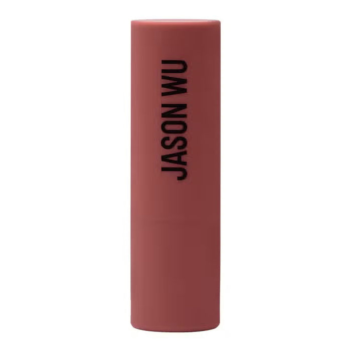 A burgundy JASON WU BEAUTY HOT FLUFF LIP/EYE/CHEEK matte lipstick stands upright with the brand name printed vertically, set against a pale pink background.