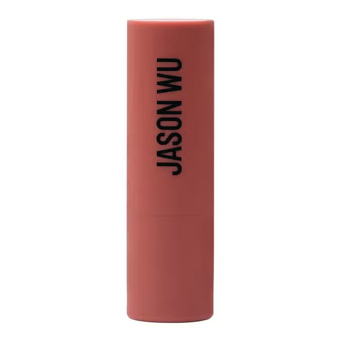 A burgundy JASON WU BEAUTY HOT FLUFF LIP/EYE/CHEEK matte lipstick stands upright with the brand name printed vertically, set against a pale pink background.
