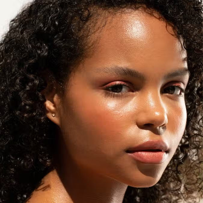 A burgundy JASON WU BEAUTY HOT FLUFF LIP/EYE/CHEEK matte lipstick stands upright with the brand name printed vertically, set against a pale pink background.
