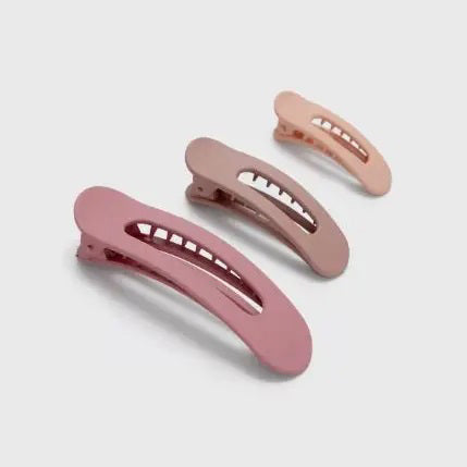 A pink card presents the KITSCH - FLAT LAY CLAW CLIP 3 PCS, featuring three clips in gradient shades of pink and mauve, from light to dark. Adorned with a logo and text, it emphasizes their crafting from recycled plastic.