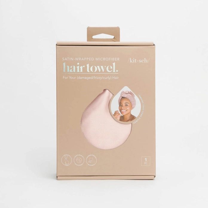 The image displays a beige box with the KITSCH Satin Wrapped Hair Towel inside. The packaging shows an illustration of the towel and a smiling person wearing it, emphasizing its benefits for reducing frizz in damaged, curly, or frizzy hair.