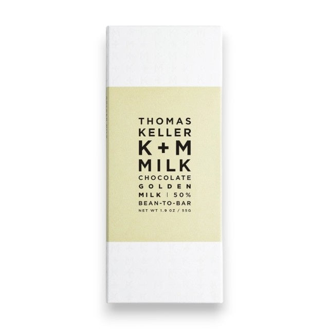 A white wrapper for K & M EXTRAVIRGIN CHOCOLATE's K+M - MILK CHOCOLATE GOLDEN MILK BAR, Net Wt. 1.9 oz/55g, with a light beige central band, black minimalist text, and highlighting Arriba Nacional Cacao.