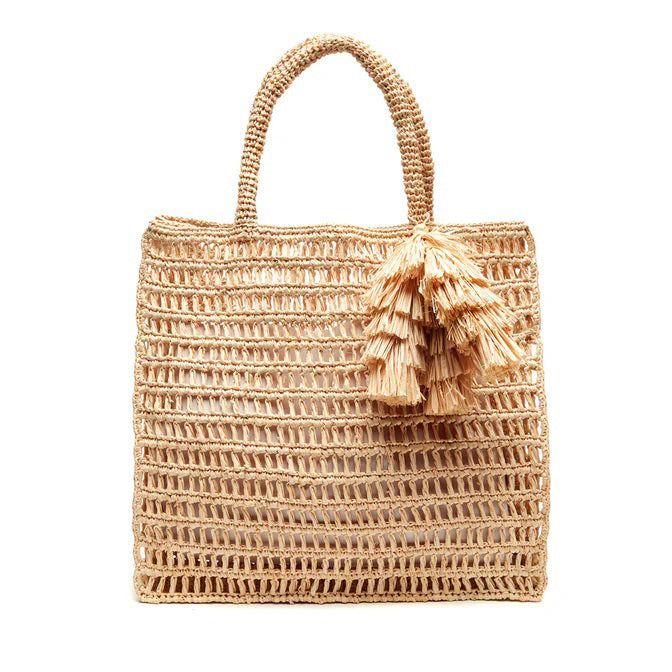 The MAR Y SOL - GEORGIA TOTE by MAR Y SOL is a rectangular crocheted raffia bag with two handles and a decorative tassel, shown against a white background.