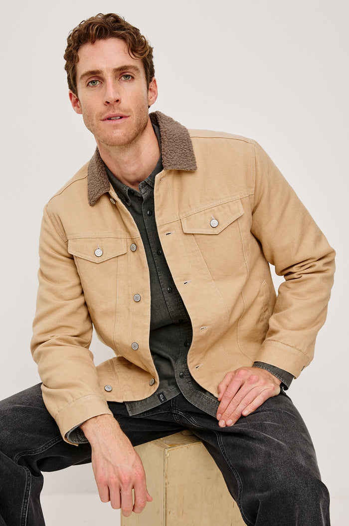 McKinley Jacket with Button Closure, Two Chest Button Flap Pockets and a Brown Contrast Collar in Duck Colorway. Front View Featured on Seated Model.
