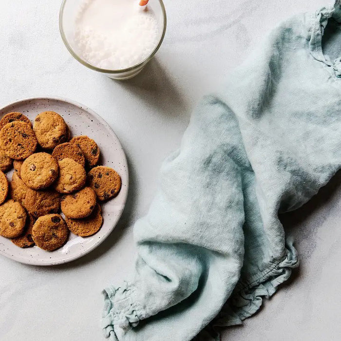 A brown, diamond-patterned box labeled "MEMAWS COUNTRY KITCHEN - CHOCOLATE CHIP COOKIES" by 1 IN 6 SNACKS features images of classic American cookies and offers homemade cookies with rich chocolate flavor. Net weight: 4 oz (113g).