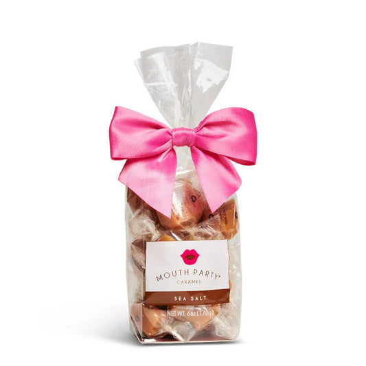 A clear bag of Mouth Party Sea Salt Caramels, tied with a bright pink bow and labeled "MOUTH PARTY - SEA SALT CARAMEL BAG.