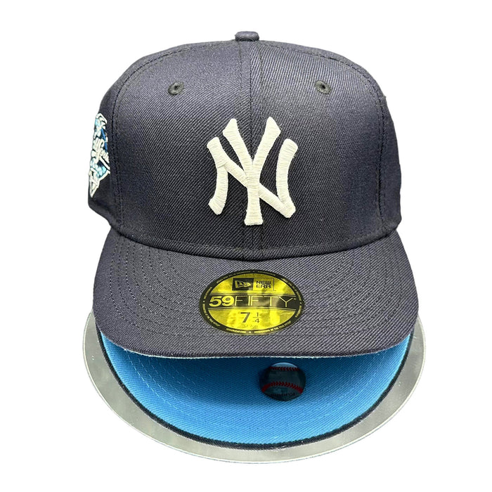 A New York Yankees navy blue fitted cap with a sky blue visor, featuring the NY logo and a patch commemorating the 2000 World Series on the side.