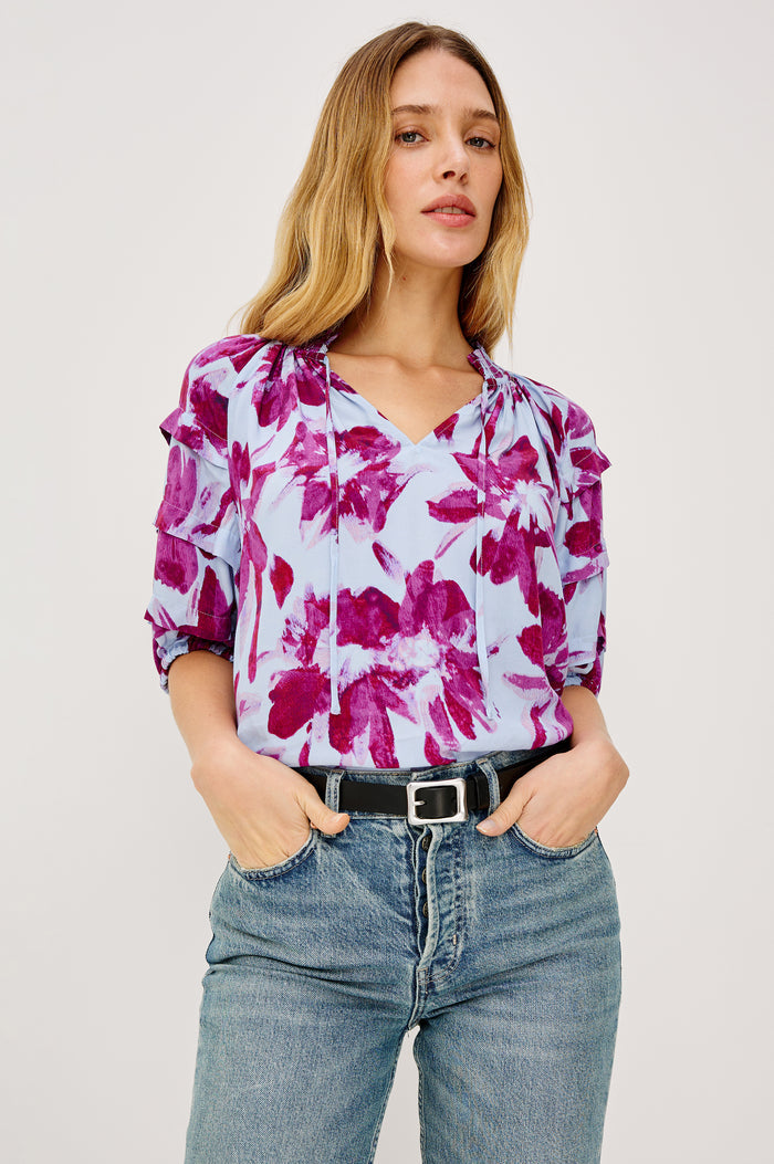 Paris Short-Sleeve Top with Shirred Collar, V-neckline with Ties, Deep Pleats on Sleeves and Elastic at the Sleeve Opening in Blue Lily Colorway, Blues and Pink- Front Tucked View Featured on Model