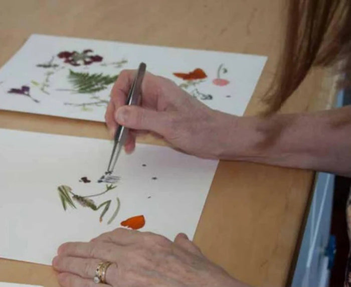 The PETAL PEOPLE PRESS - GET WELL SOON CARD by PETAL PEOPLE PRESS showcases a whimsical figure made from leaves and flowers on a simple-lined bed. The earthy-toned person, resembling a closed flower bud with raised arms, makes it perfect for a botanical-themed card.