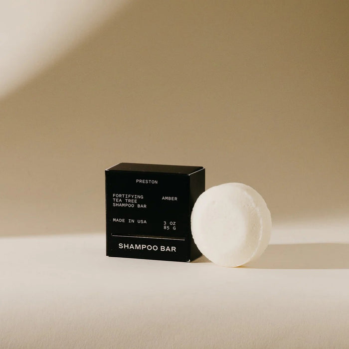 A black box labeled “PRESTON - SHAMPOO BAR” from the brand PRESTON rests on a beige surface with soft shadows. This 3 oz sulfate-free, USA-made bar offers an eco-friendly, plastic-free shampoo solution.