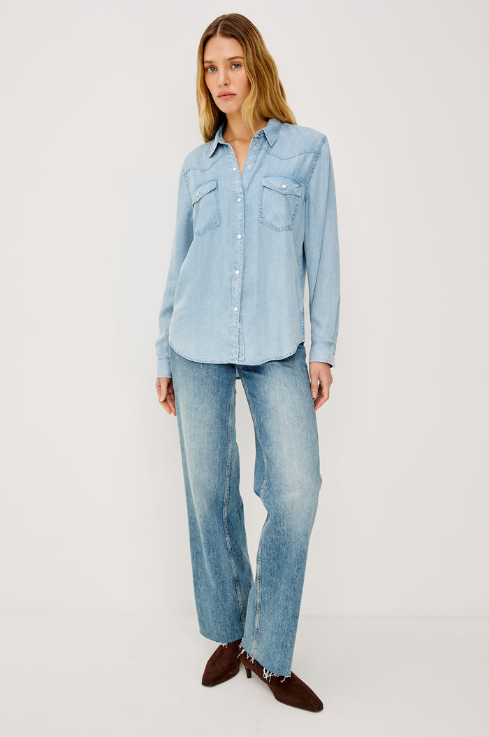 Remi is a utility-style Tencel denim shirt with a relaxed fit. The shirt features a notched collar, two front flap pockets, and faux horn buttons etched with a logo in medium indigo colorway - Front View Featured on Model