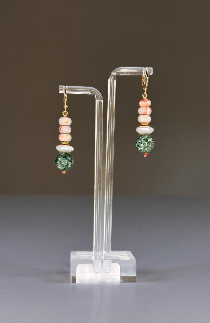 The SELENA EARRINGS by SANDRINE FRANCE STUDIO are gold hoops with stacked beige and brown marbled beads, a white pearl-like accent, gold spacer, and a large green-and-white Tree Agate bead, displayed on a plain background.