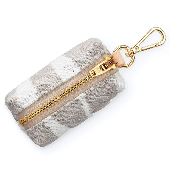 The Foggy Dog’s WASTE BAG DISPENSER (SANDSTONE ZEBRA) is a stylish small pouch with a beige and white pattern, gold zipper, and clasp—perfect for carrying eco-friendly waste bags during your walks.