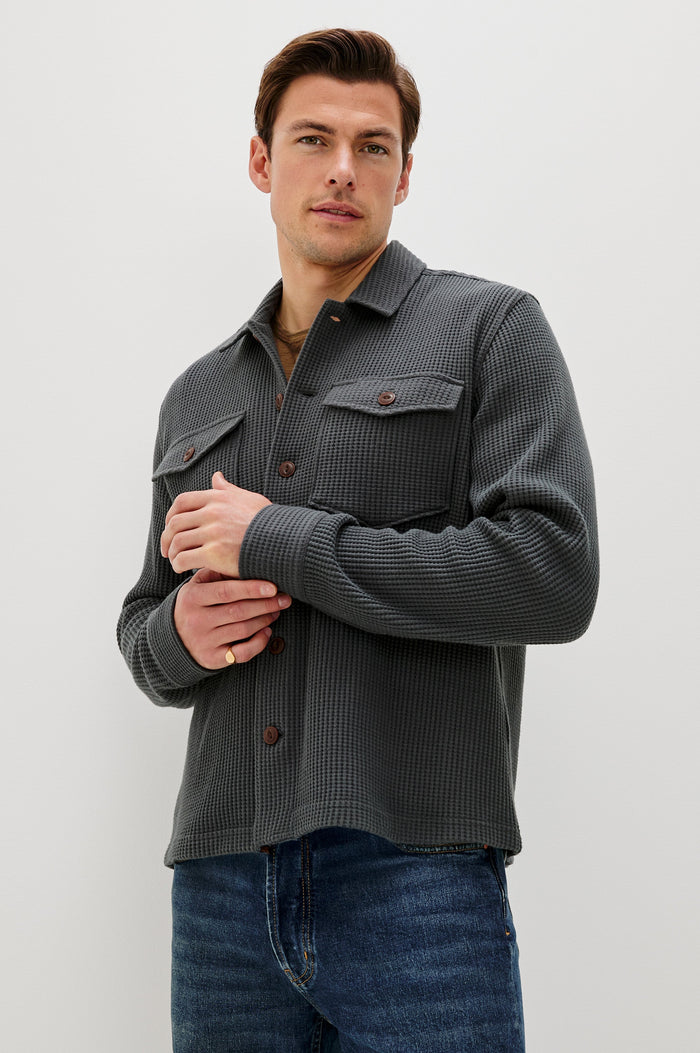 The Wells is a collared button front shirt jacket with contrast brown buttons and two chest pockets in Ink colorway. Front  view featured on model.