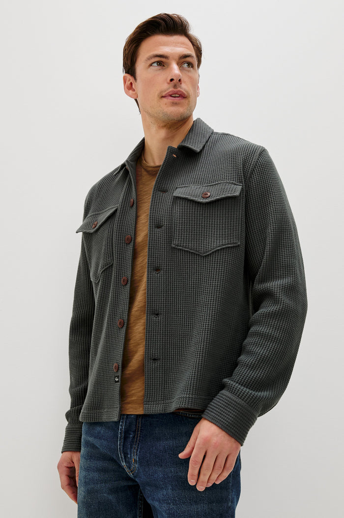 The Wells is a collared button front shirt jacket with contrast brown buttons and two chest pockets in Ink colorway. Front  view featured on model.