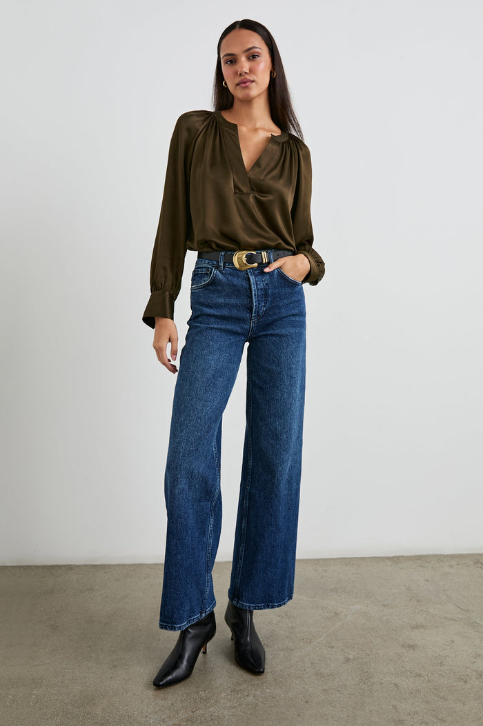 Wynna Long-Sleeve Top with a Deep V Neck and Ruching above the Cuffs and at the Neckline in Dark Moss Colorway - Front Tucked Full Body View Featured on Model